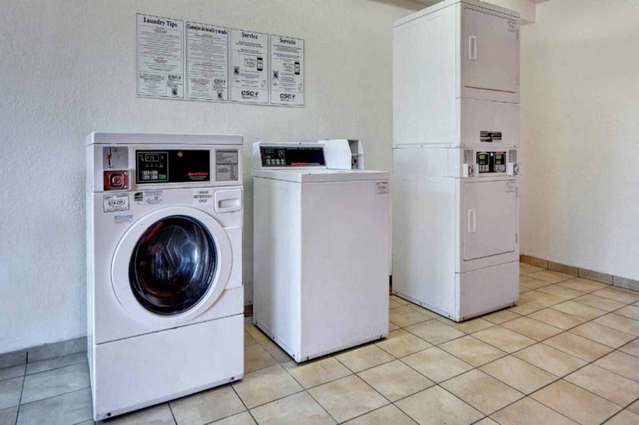 A laundry facility with a front-loading washer, a dryer, and a cabinet with a control panel.