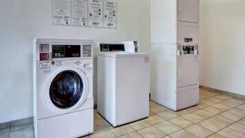 A laundry facility with a front-loading washer, a dryer, and a cabinet with a control panel.
