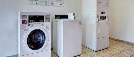 A laundry facility with a front-loading washer, a dryer, and a cabinet with a control panel.