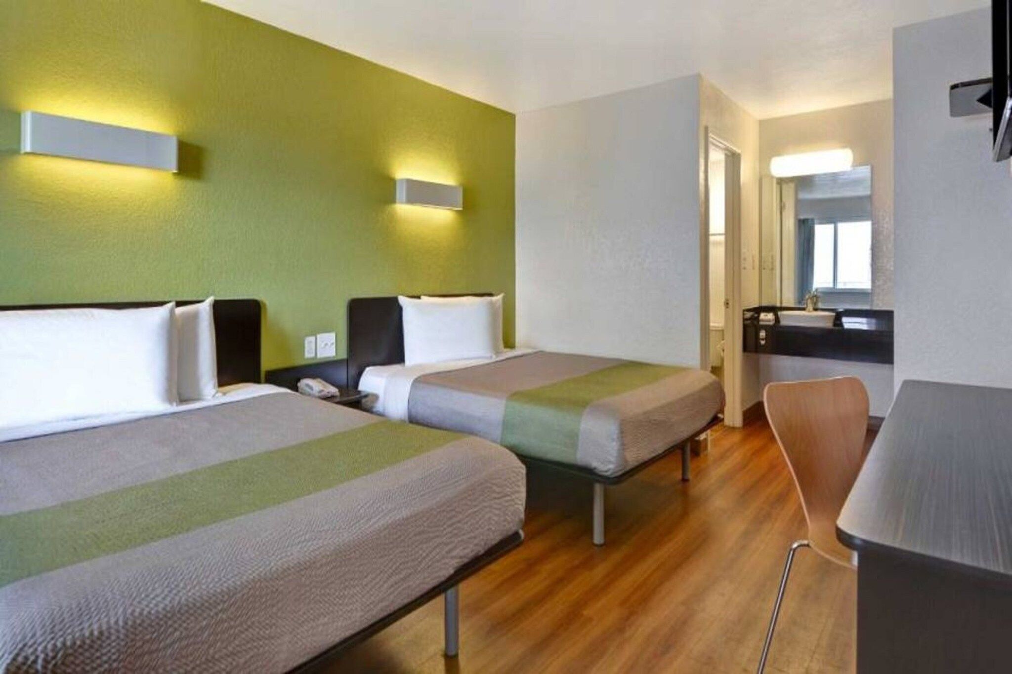A hotel room with two beds, a desk, and a chair.