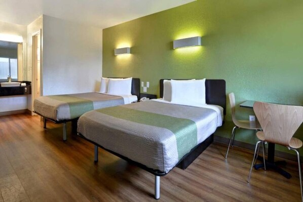 A hotel room with two beds, a desk, and a chair.