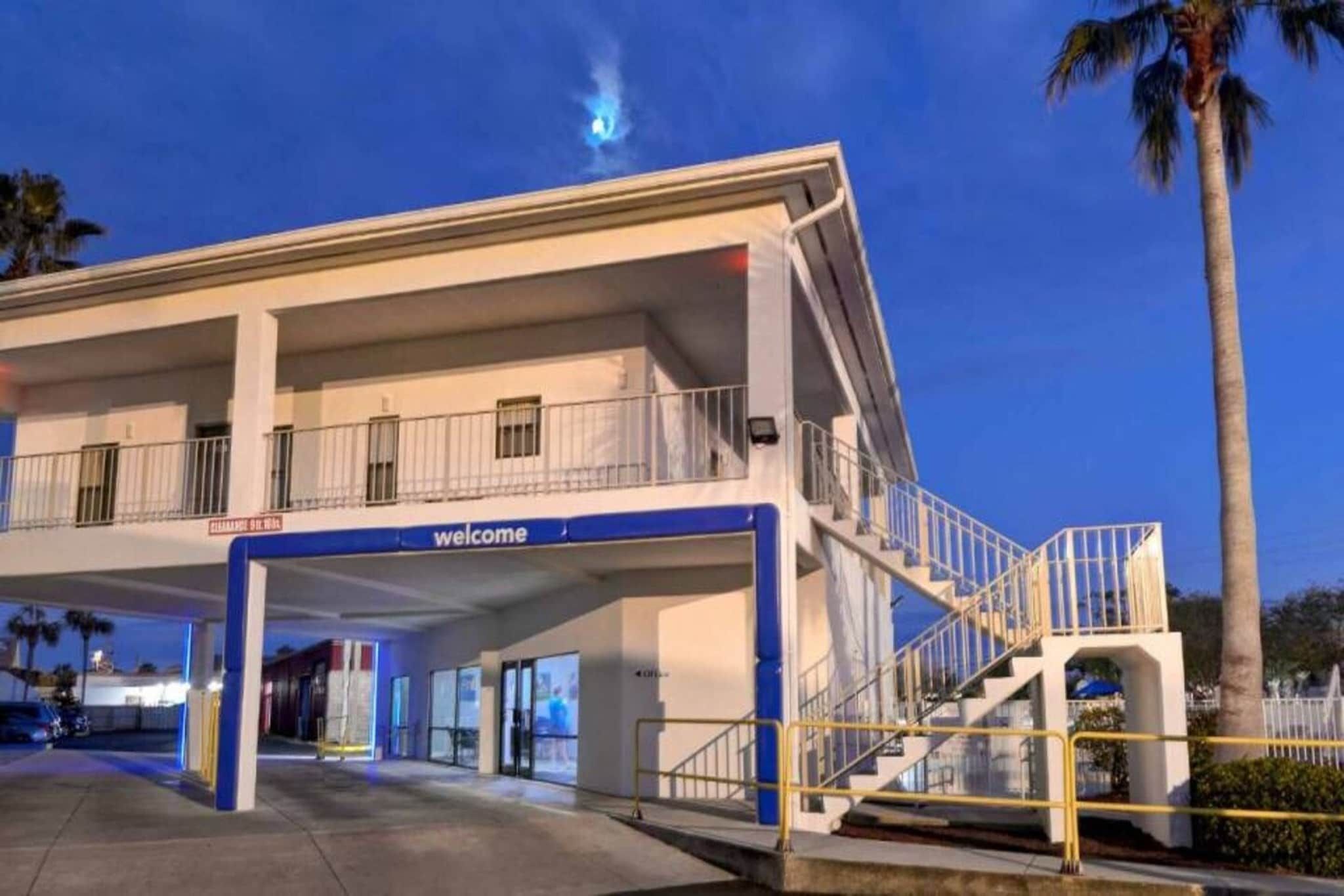 A hotel entrance with a 'welcome' sign, a covered parking area, and a staircase leading to the upper level.