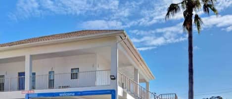 Un edificio con un cartel de 'welcome', un vestíbulo cubierto y una escalera que conduce a un nivel superior.