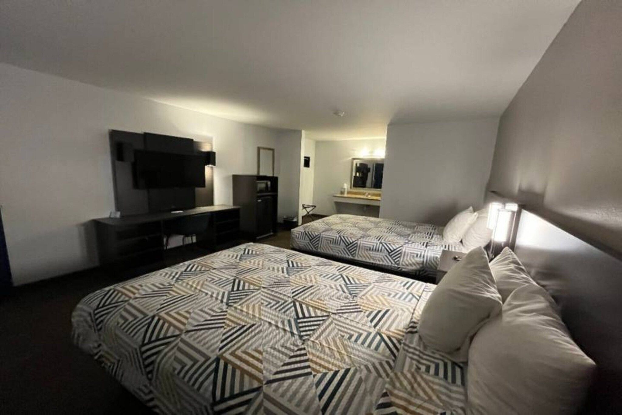 Een hotelkamer met twee bedden, een bureau, een televisie en een spiegel.