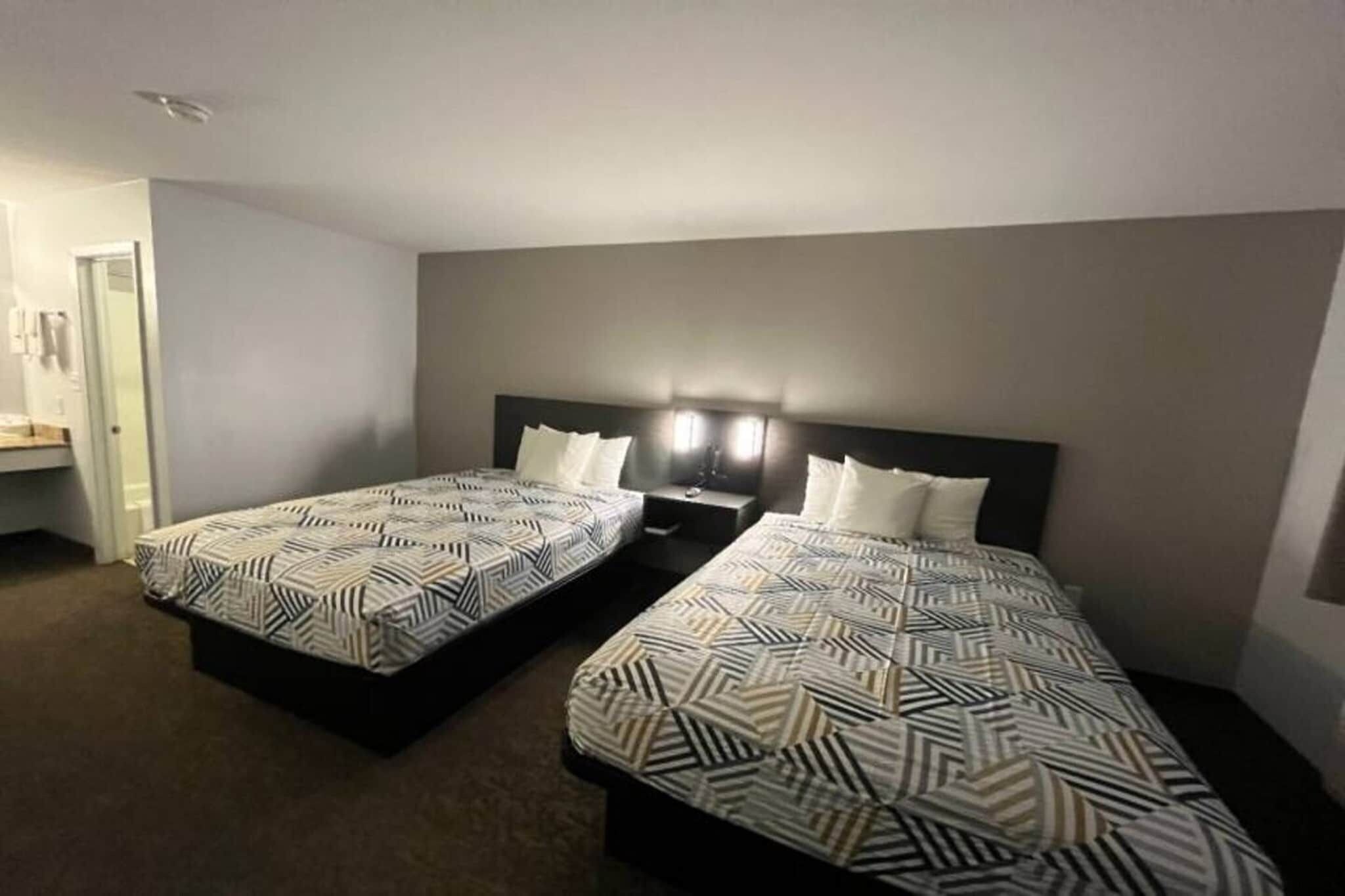Een hotelkamer met twee enkele bedden, een nachtkastje en een wandlamp.