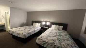 Een hotelkamer met twee enkele bedden, een nachtkastje en een wandlamp.