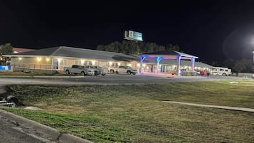 Een motel met een parkeerplaats, een overdekt buitengebied en een bord waarop 'Nu vertrekken' staat.