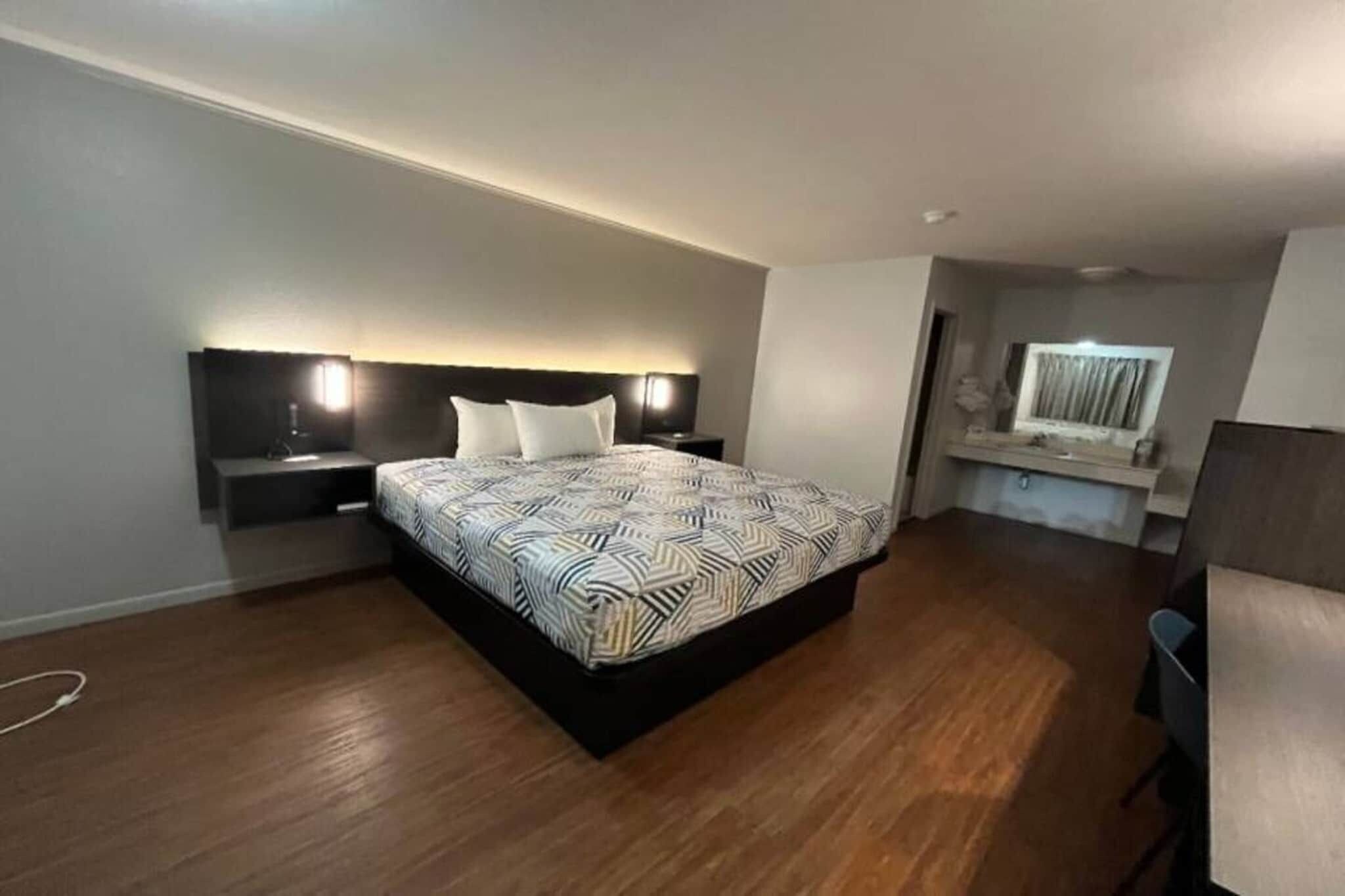 A modern bedroom with a large bed, bedside tables, a desk, and a chair.