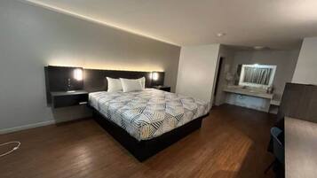 A modern bedroom with a large bed, bedside tables, a desk, and a chair.