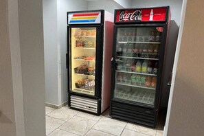Two beverage vending machines, one with a rainbow-colored top and the other with a red Coca-Cola logo.