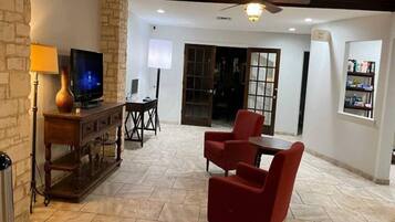A living room with a television, a lamp, a red chair, a small table, and a bookshelf.