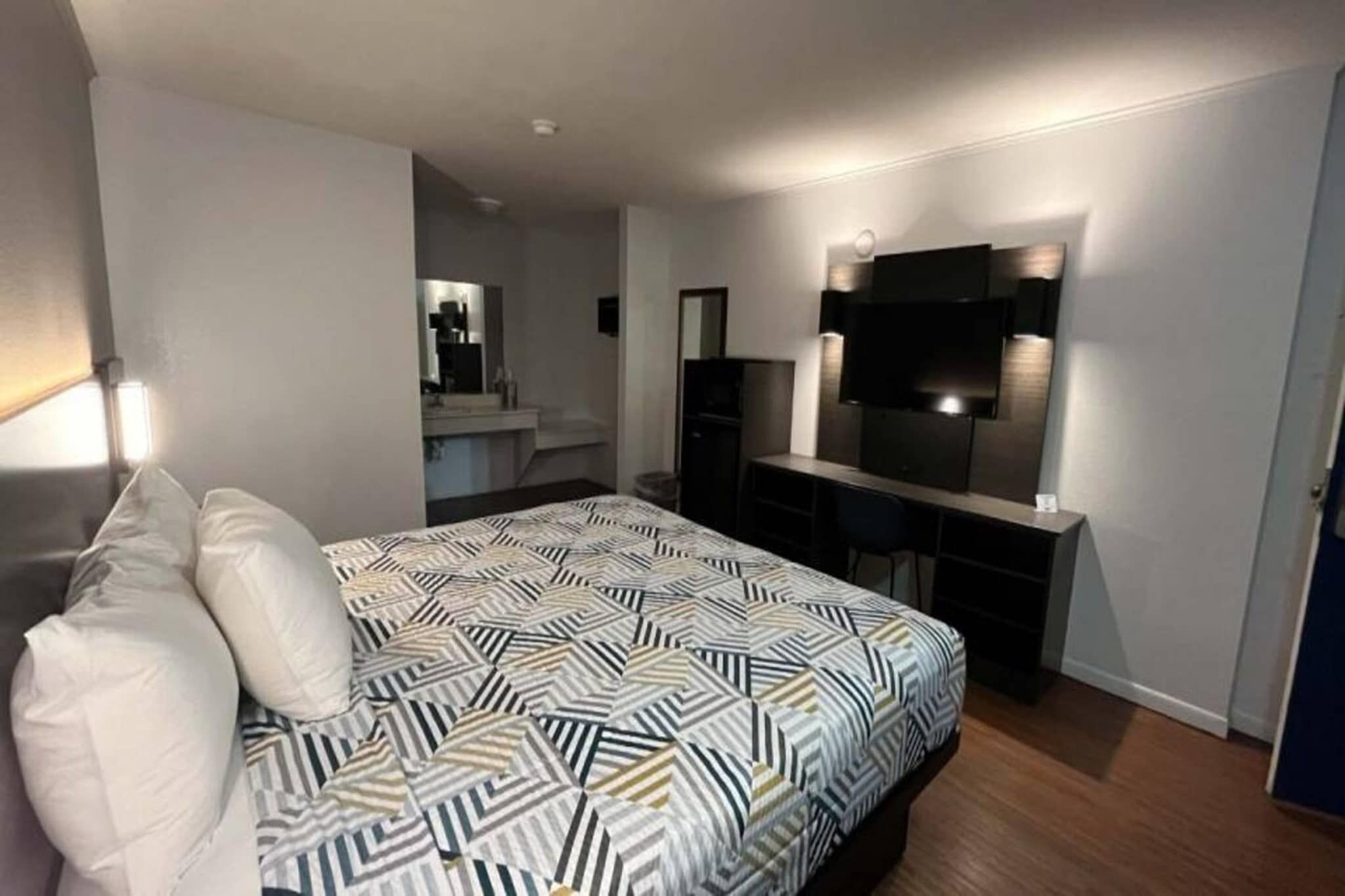 Quarto moderno com cama, escrivaninha e televisão.
