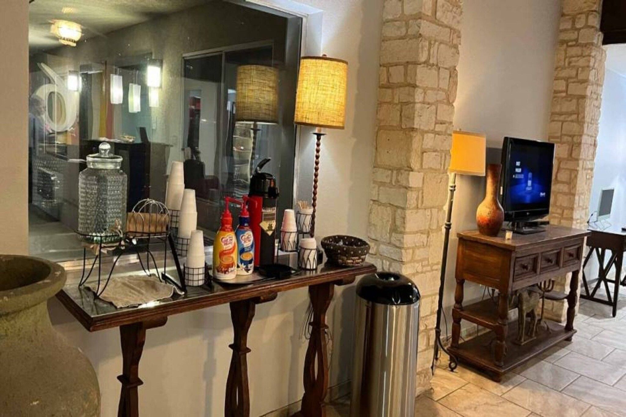 A kitchen counter with various items like a coffee maker, condiment bottles, and a trash can.