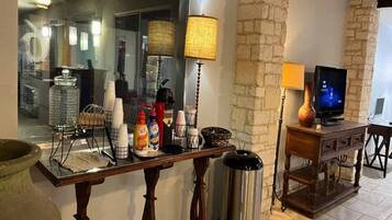 A kitchen counter with various items like a coffee maker, condiment bottles, and a trash can.