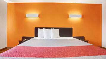 Habitación de hotel con una cama grande, dos mesitas de noche y dos lámparas de pared.