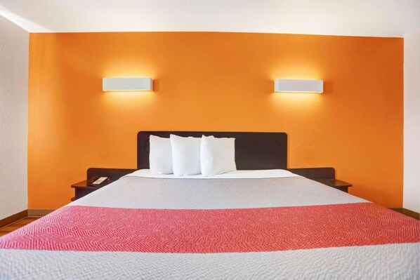 A hotel room with a large bed, two bedside tables, and two wall-mounted lamps.