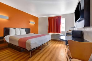 A hotel room with a bed, a desk, a chair, a TV, and a window with curtains. - MS6 Truth Or Consequences |1 King Bed (Truth or Consequences,NM)
