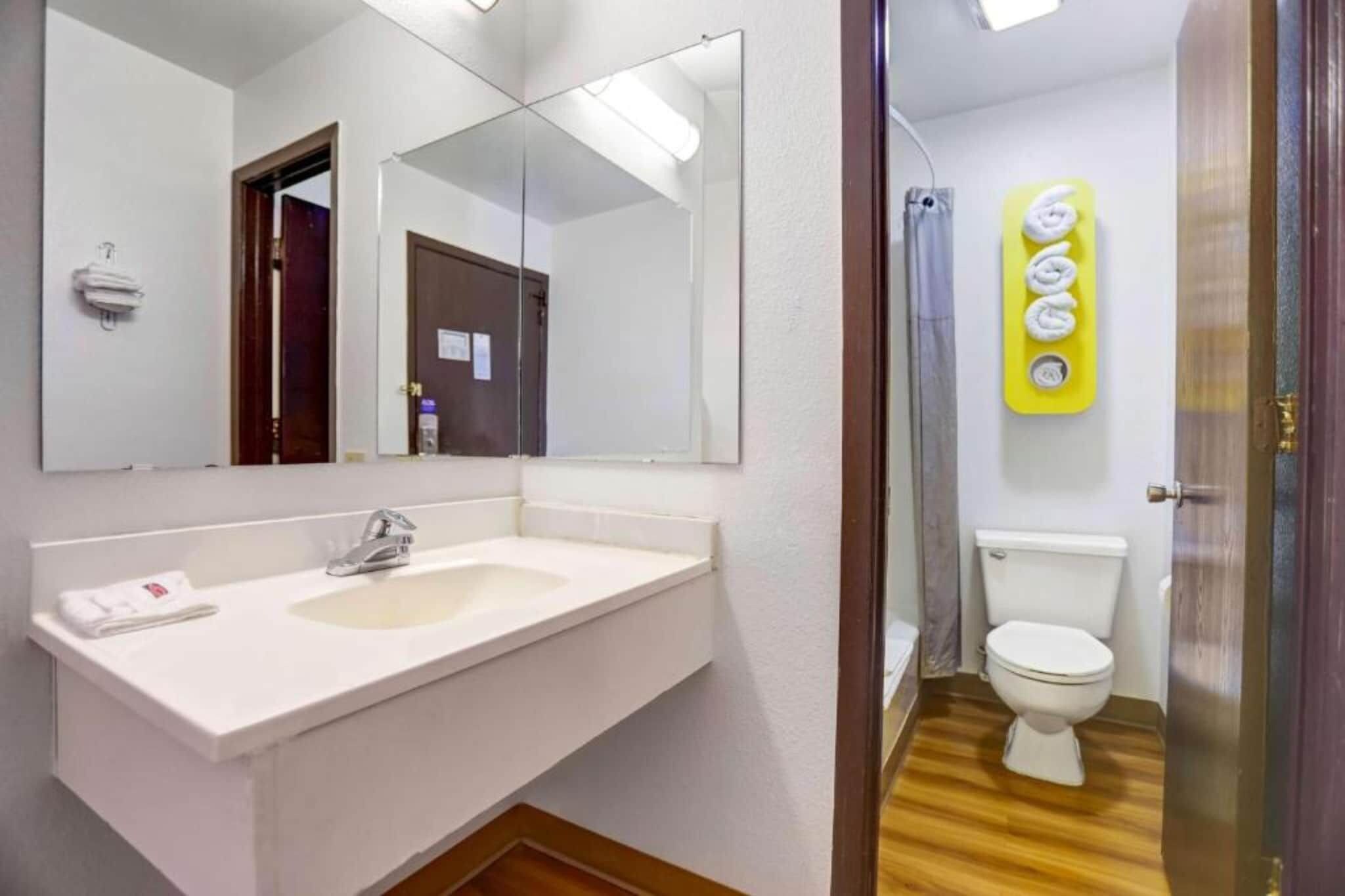 A bathroom with a white sink, a mirror, a toilet, and a shower area.