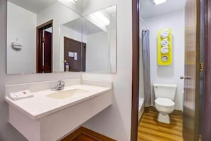 A bathroom with a white sink, a mirror, a toilet, and a shower area. - MS6 Truth Or Consequences |1 King Bed (Truth or Consequences,NM)