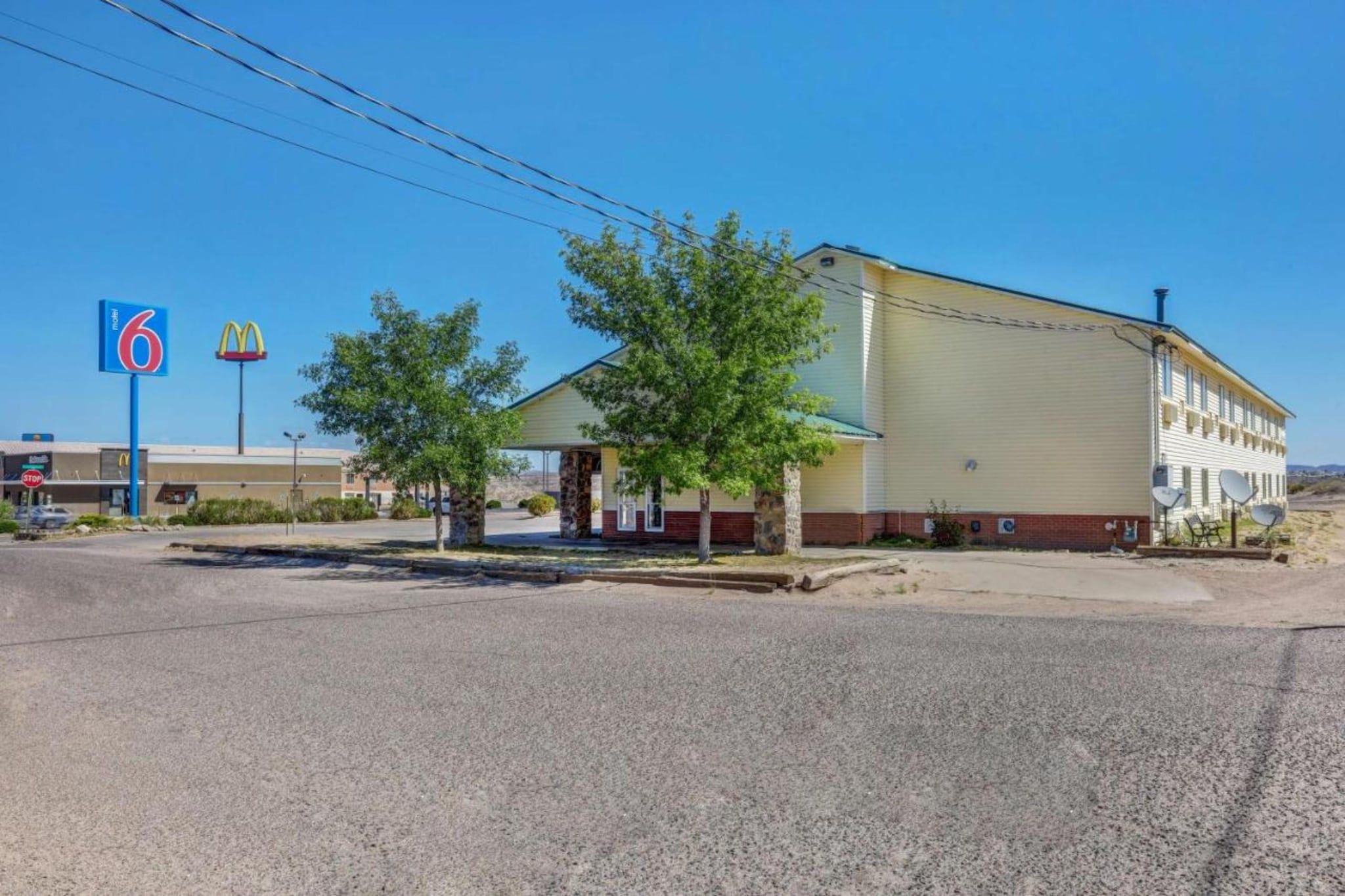 A motel with a large building, a McDonald's sign, and a 6 Motel sign.