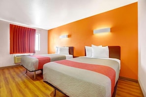 A hotel room with two beds, a window with red curtains, and an orange accent wall. - 2 Queen Beds | Non-Smoking (Truth or Consequences)