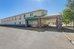 A motel with a covered parking area and a stone pillar.