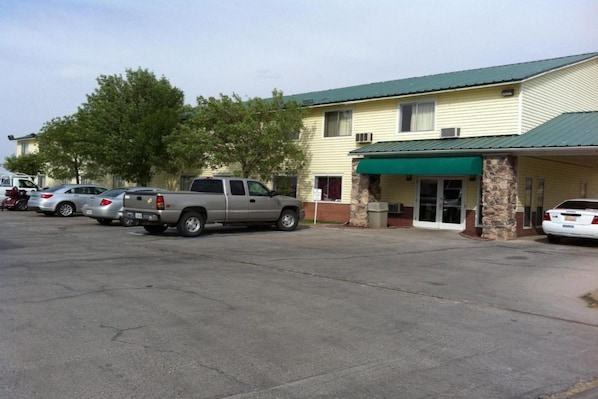 A building with a green awning, a parking lot with several cars, and a stone pillar. - 2 Queen Beds | Non-Smoking (Truth or Consequences)