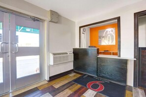 A hotel reception area with a reception desk, a clock, and a door with push buttons. - 2 Queen Beds | Non-Smoking (Truth or Consequences)
