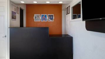 A reception area with a black counter, orange wall, and framed pictures.
