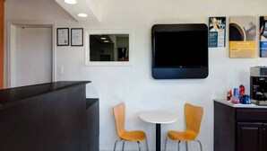 A reception area with a counter, two chairs, a small table, a flat-screen TV, and a coffee machine. - 2 Queen Beds|Nsmk,Micfridge (Rolla)