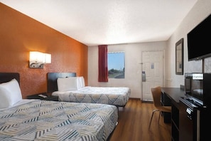 Ein Hotelzimmer mit zwei Betten, einem Schreibtisch, einem Sessel, einem Fernseher und einem Fenster mit Blick.