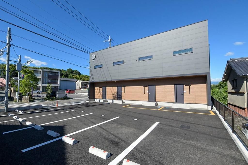 A parking lot with marked spaces and a modern building with a flat roof and large windows.