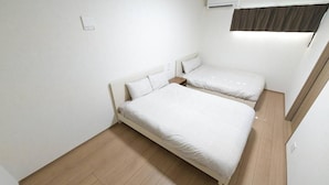 Ein Zimmer mit zwei Betten, Holzboden und einer Klimaanlage.