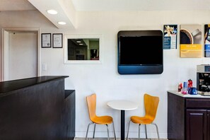 Ein Empfangsbereich mit einer Theke, zwei Stühlen, einem Fernseher und einer Kaffeemaschine.