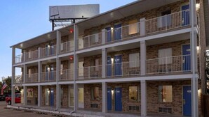Een motel met meerdere verdiepingen, een gevel van baksteen, balkons en een parkeerplaats.