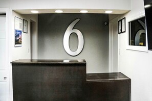 A reception desk with a large number '6' on the wall, a framed certificate, and a window with a view. - 1 King Bed|Nsmk,Micfridge (Rolla)