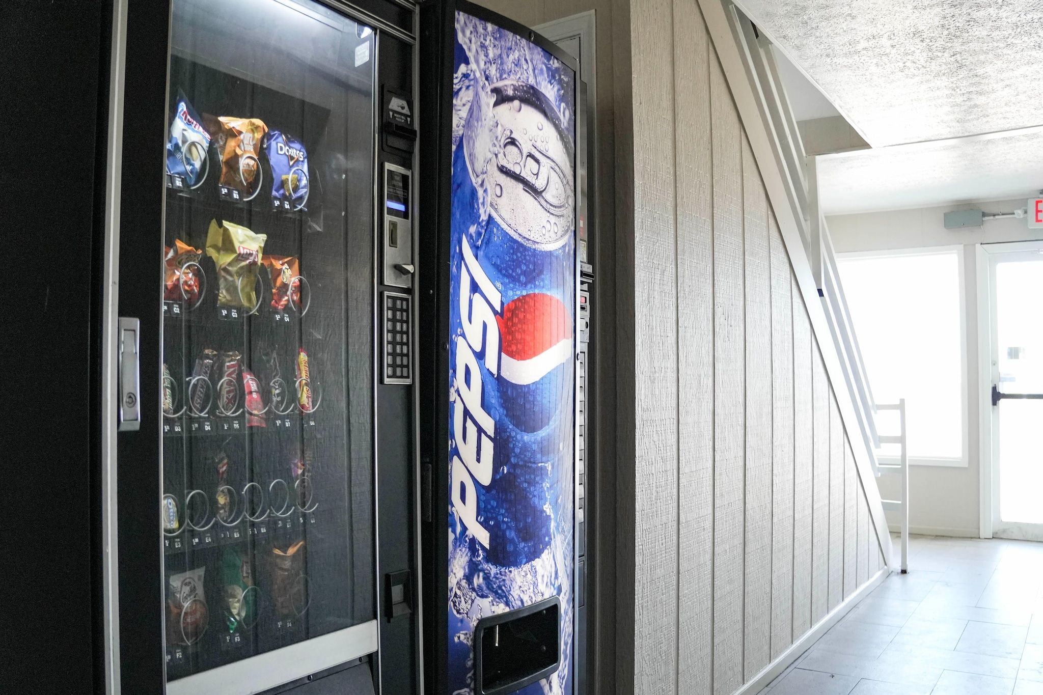 A vending machine with a Pepsi logo and a snack vending machine with various snacks.