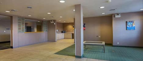 A hotel lobby with a reception desk, a counter, and a seating area.