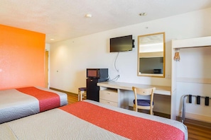 Habitación de hotel con dos camas, un escritorio con silla, televisor, espejo y armario.