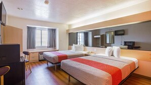 Ein Hotelzimmer mit zwei Betten, einem Schreibtisch, einem Stuhl, einem Fernseher und einem Fenster mit Vorhängen.
