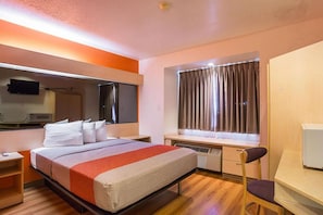 A hotel room with a bed, bedside table, desk, chair, window with curtains, and a flat-screen TV. - 1 Queen Bed | Mobility Accessible Tub Nsmk (Bernalillo)