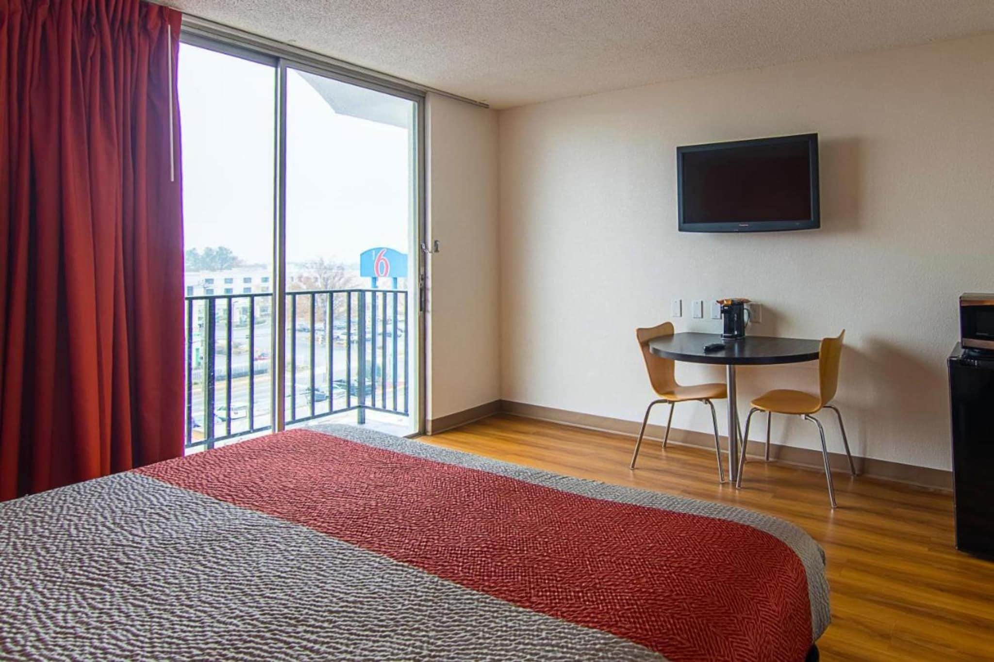 Une chambre d’hôtel avec un lit, une petite table et des chaises, un téléviseur fixé au mur et un balcon avec vue.