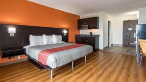 Habitación de hotel con cama, escritorio, microondas y puerta que da a otra habitación.