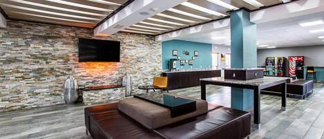 A modern lounge area with a stone wall, leather seating, a flat-screen TV, and a coffee bar.