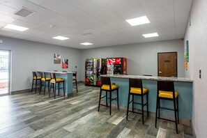 Een bar met een aanrecht en barkrukken, automaten en een deur.