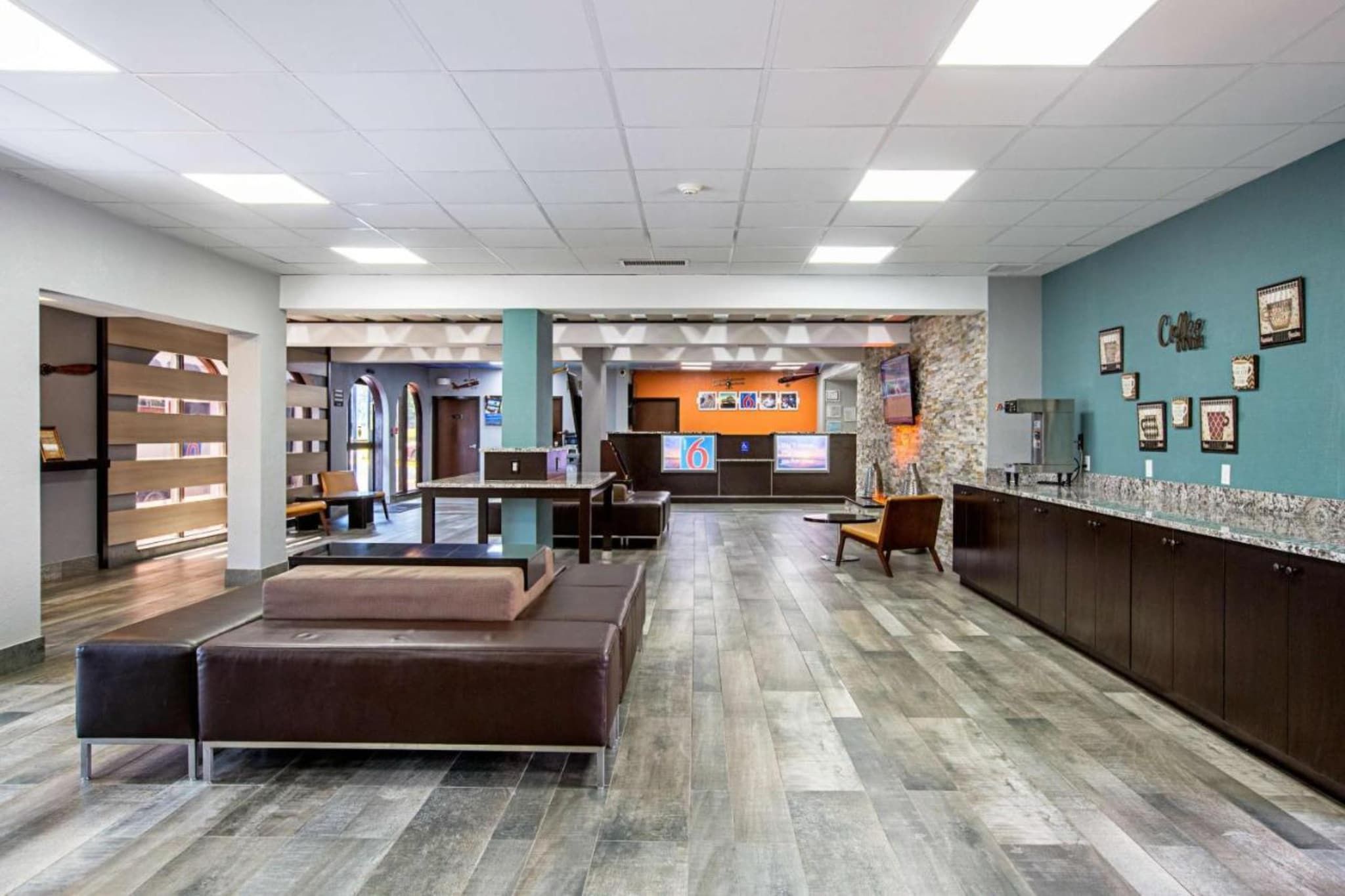 A spacious lobby with a reception desk, seating area, and a wall with framed pictures.