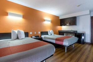 Ein Hotelzimmer mit zwei Betten, einem Schreibtisch, einer Mikrowelle und einem kleinen Kühlschrank.