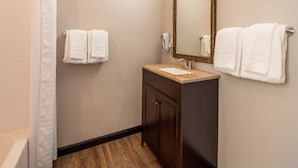Ein Badezimmer mit Dusche, Waschbecken, Spiegel und zwei Handtüchern.