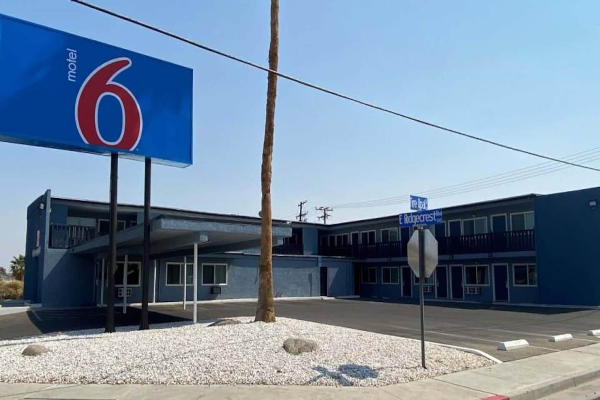 Un motel con un gran letrero azul, un estacionamiento y un edificio con múltiples ventanas.