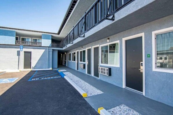 A building with a series of doors and windows, a ramp, and a no parking sign.